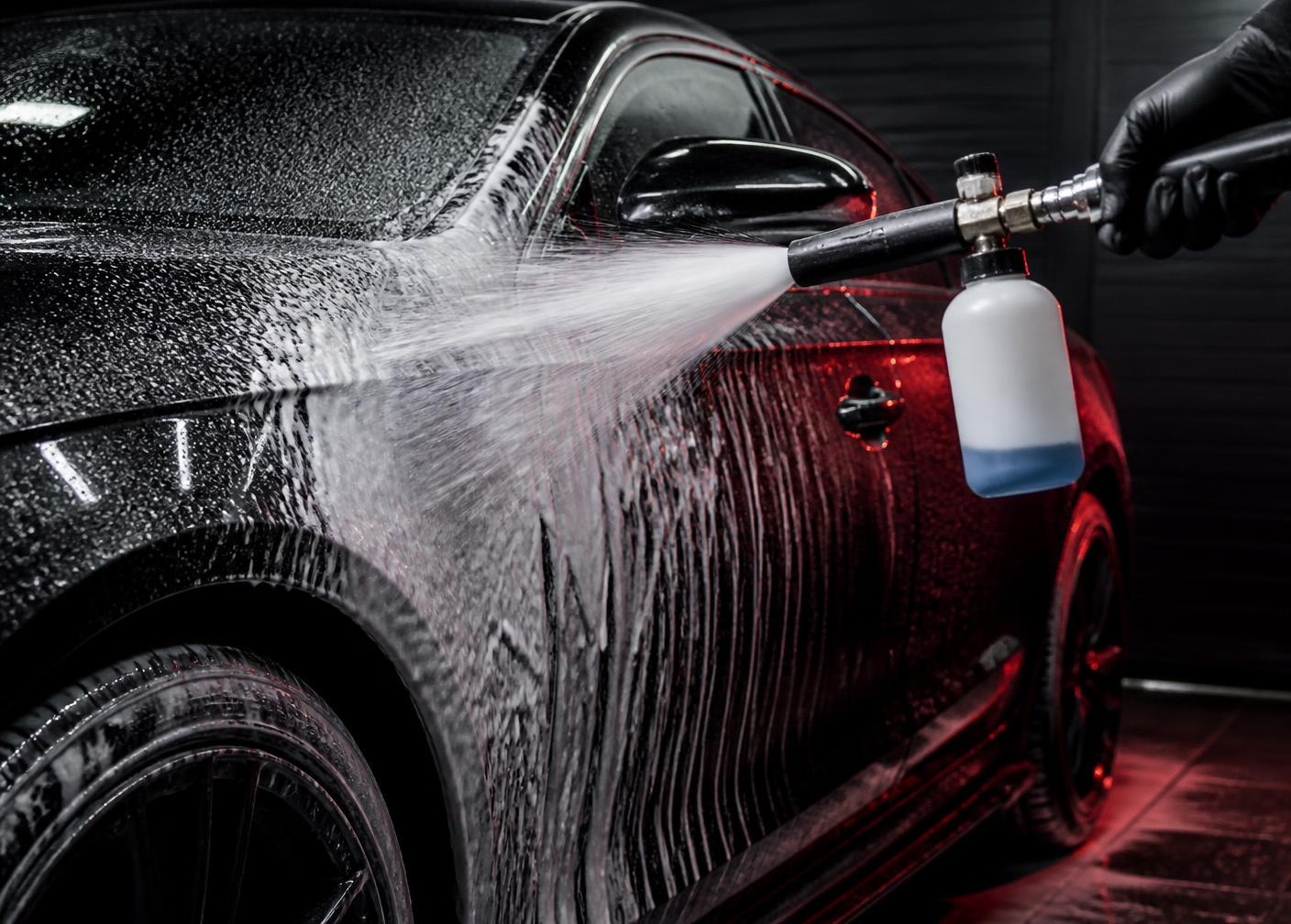 Snow foam applied by a professional foam cannon across the wet black paint of a premium car during a KingWash Exterior Detail
