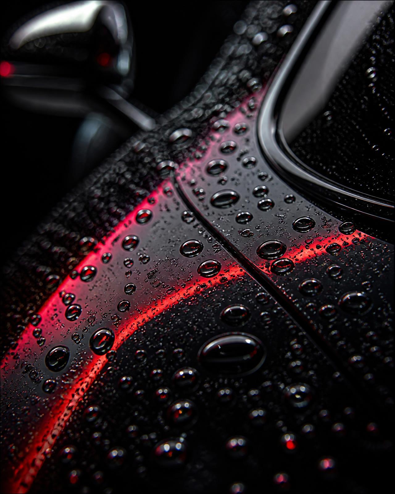 Hard light raking across a polished black panel, showing the finish after a KingWash detail
